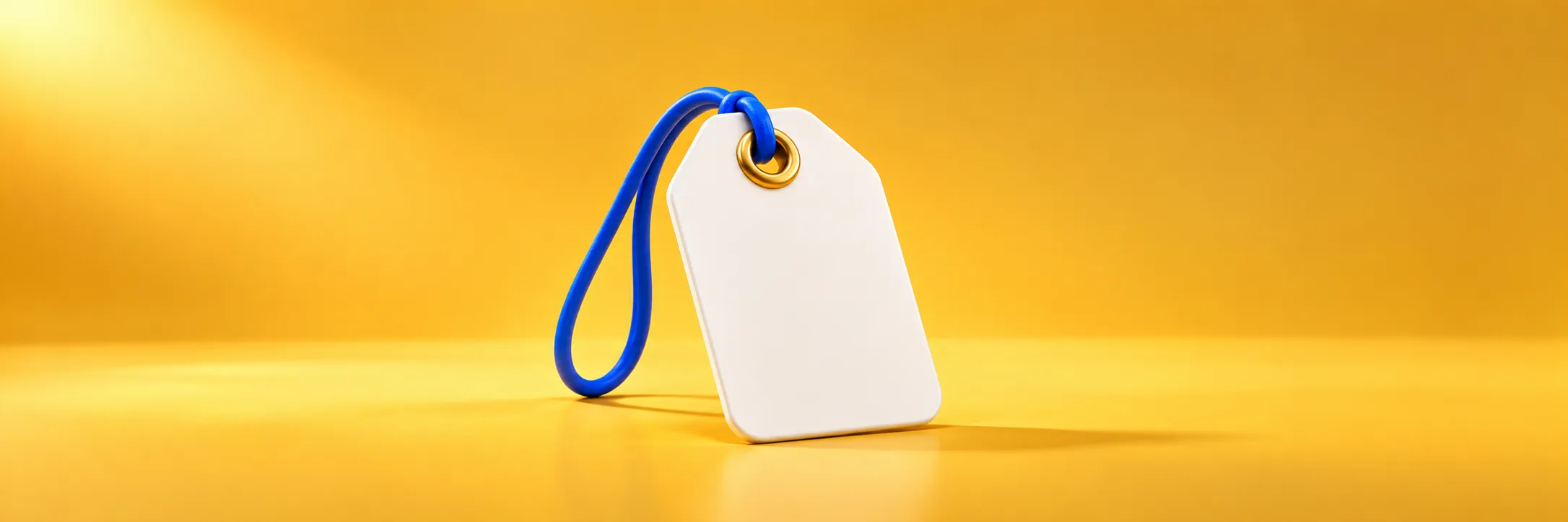 Une grande étiquette de prix blanche et vierge, avec un œillet doré et une cordelette bleue, sur fond jaune de studio, pour les honoraires de notre agence Google Ads